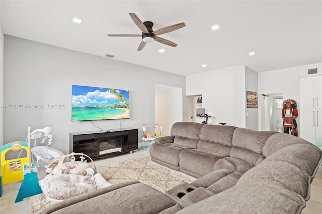 living area featuring recessed lighting, visible vents, a glass covered fireplace, and a ceiling fan