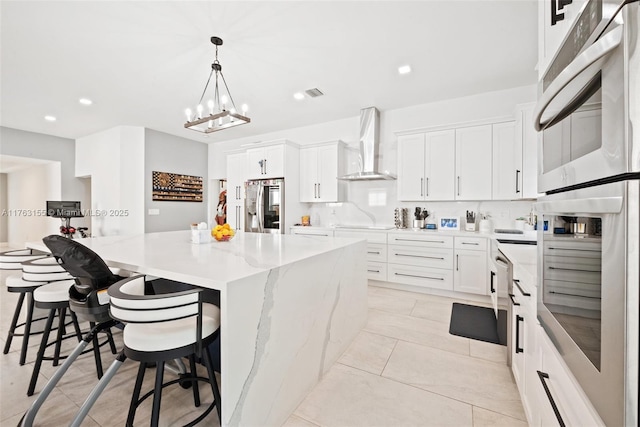 kitchen featuring stainless steel appliances, a spacious island, white cabinets, and wall chimney range hood