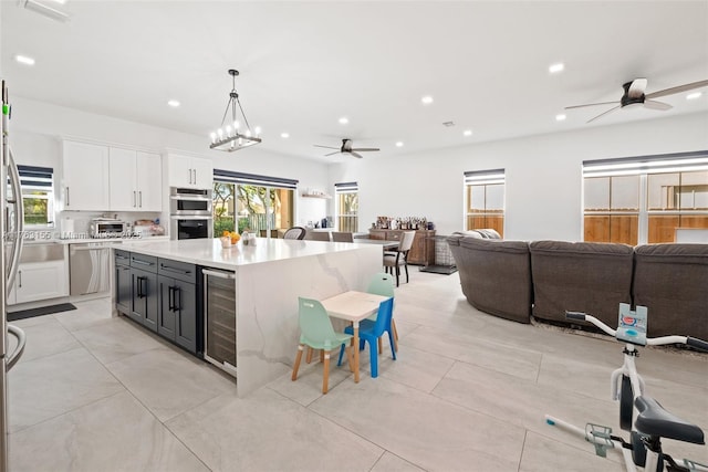 kitchen featuring a kitchen island, light countertops, wine cooler, white cabinets, and open floor plan