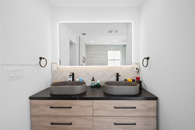 full bathroom with double vanity, visible vents, decorative backsplash, and a sink