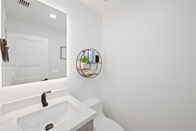 half bathroom with visible vents, toilet, and vanity