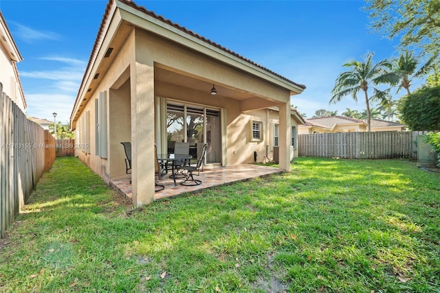 back of property with a patio, a fenced backyard, stucco siding, a tile roof, and a lawn