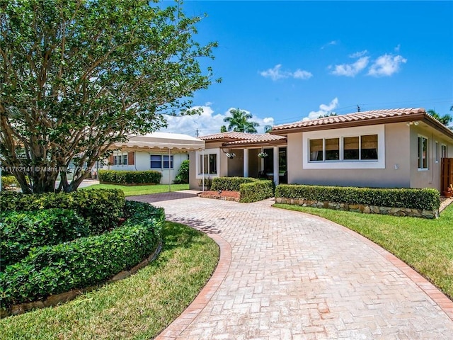 ranch-style house with decorative driveway, a tile roof, and stucco siding