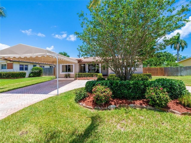 ranch-style home with decorative driveway, a front lawn, and fence