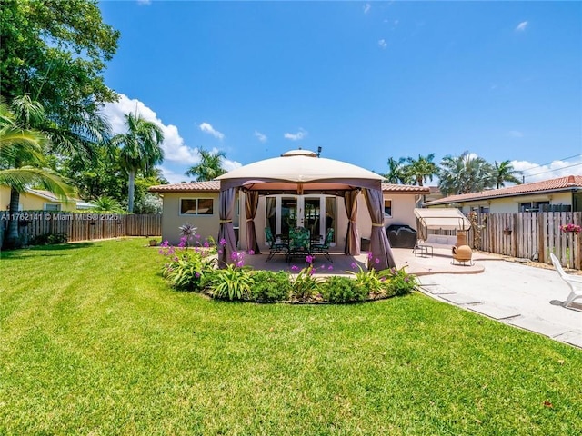 back of house featuring a yard, a fenced backyard, stucco siding, a gazebo, and a patio area