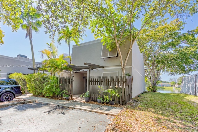 view of front of property featuring a gate, stucco siding, a water view, and fence