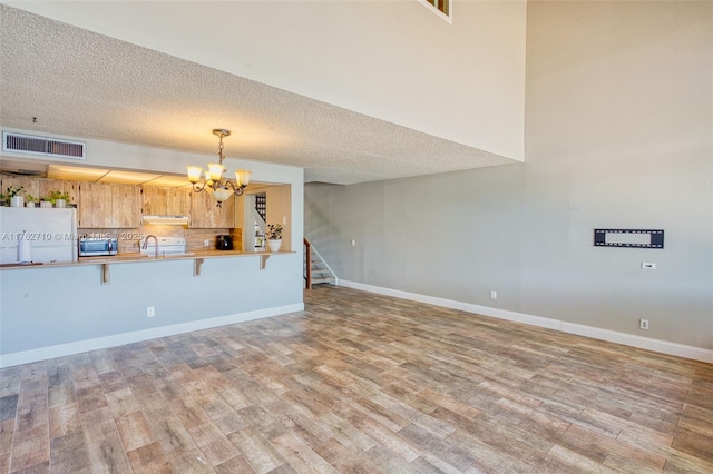 1548 NW 113th Way, Pembroke Pines, FL 33026 - unfurnished living room with stairway, wood finished floors, baseboards, a chandelier, and a textured ceiling