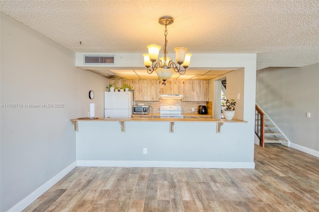 1548 NW 113th Way, Pembroke Pines, FL 33026 - kitchen featuring light wood finished floors, under cabinet range hood, visible vents, stainless steel microwave, and a notable chandelier