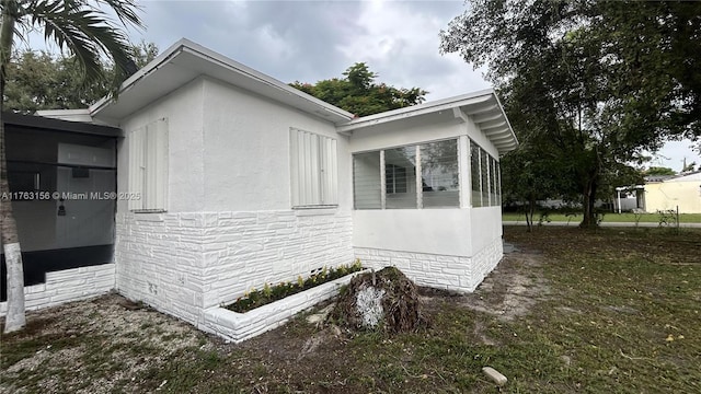 view of side of home featuring a sunroom and stucco siding