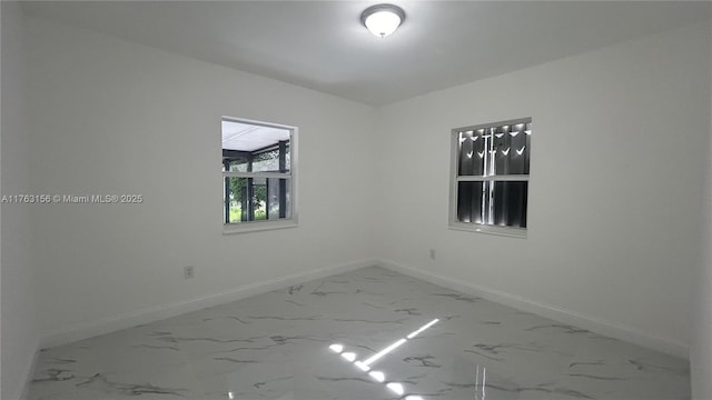 spare room with baseboards and marble finish floor