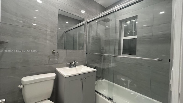 bathroom with tile walls, toilet, decorative backsplash, shower / bath combination with glass door, and vanity