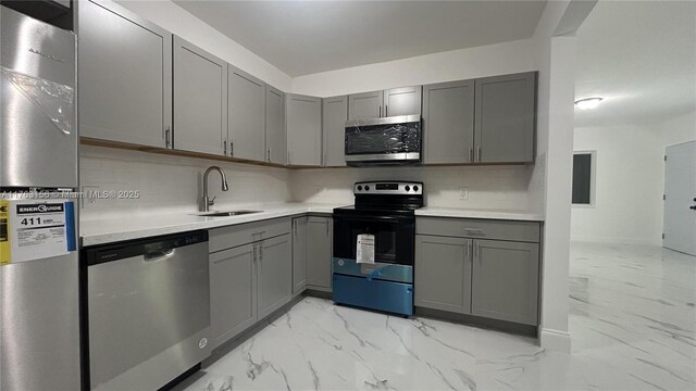 205 Seaman Ave, Opa-Locka, FL 33054 - kitchen with marble finish floor, gray cabinetry, a sink, appliances with stainless steel finishes, and decorative backsplash