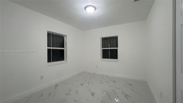 unfurnished room featuring baseboards and marble finish floor