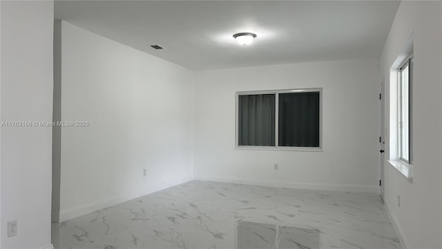 empty room featuring visible vents, marble finish floor, a healthy amount of sunlight, and baseboards