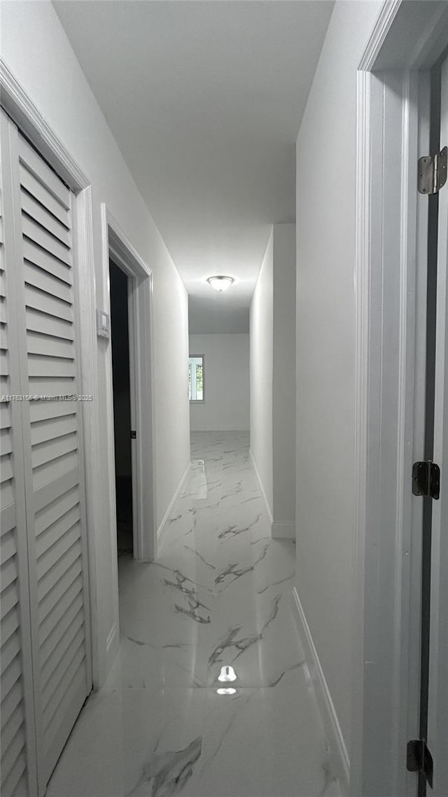 corridor featuring baseboards and marble finish floor