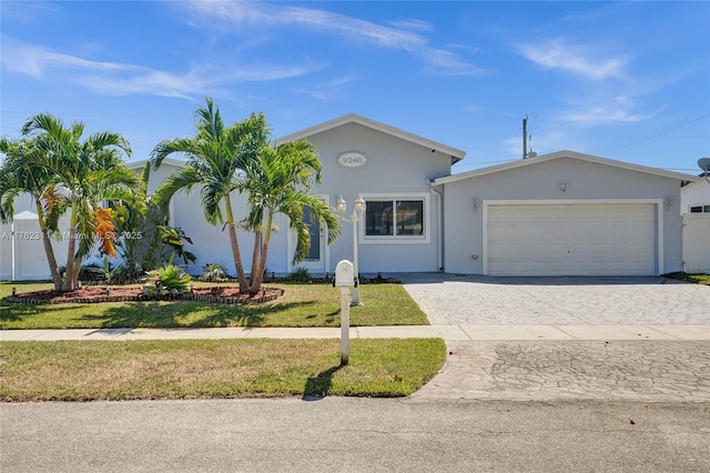 ranch-style home with stucco siding, an attached garage, decorative driveway, and a front yard