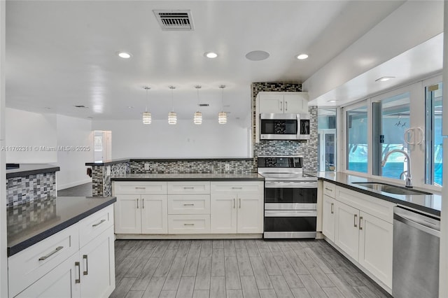 kitchen with a sink, stainless steel appliances, dark countertops, and visible vents