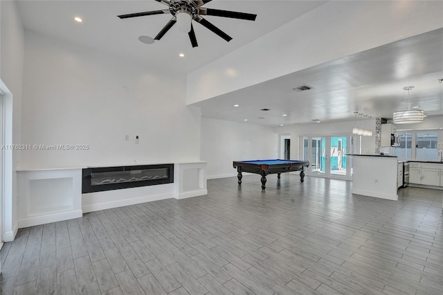 recreation room with visible vents, baseboards, recessed lighting, wood finished floors, and a glass covered fireplace