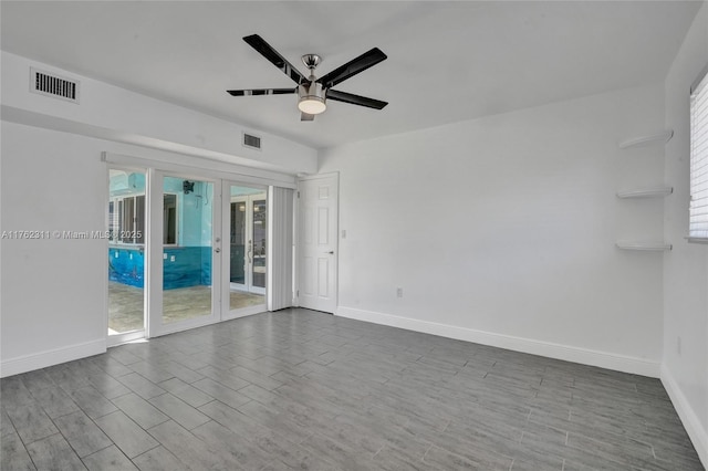 unfurnished room featuring dark wood-style floors, visible vents, ceiling fan, and baseboards