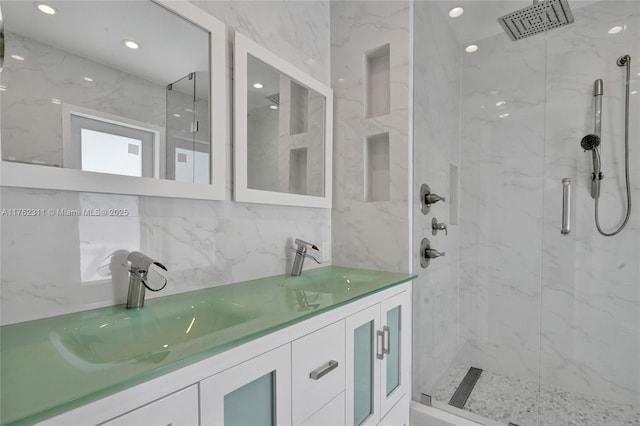 full bath with a marble finish shower, double vanity, and a sink