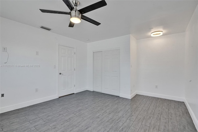 unfurnished room with visible vents, baseboards, wood finished floors, and a ceiling fan