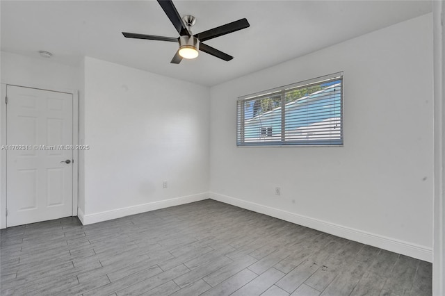 empty room with a ceiling fan, wood finished floors, and baseboards