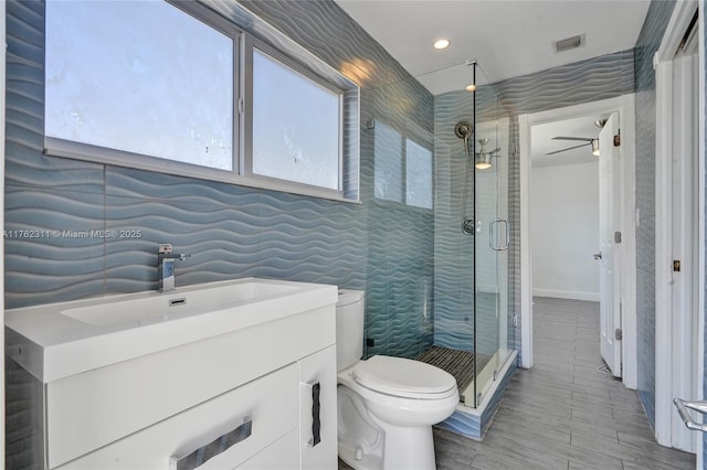 bathroom with visible vents, toilet, tile walls, a shower stall, and vanity