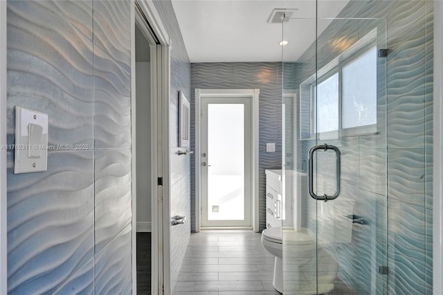 bathroom with toilet, wood finished floors, visible vents, and a stall shower