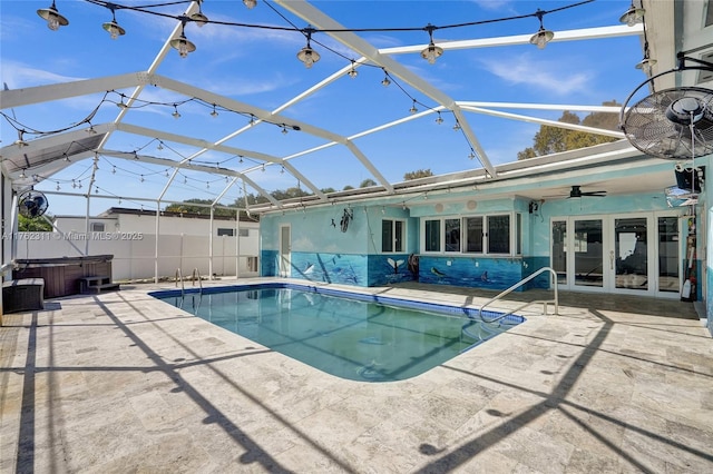 outdoor pool with a hot tub, fence, a lanai, french doors, and a patio area