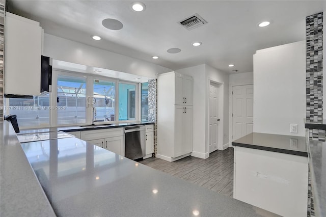 kitchen with wood finished floors, visible vents, white cabinetry, a sink, and stainless steel dishwasher