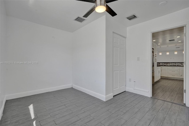 unfurnished room featuring visible vents, ceiling fan, baseboards, and wood finish floors