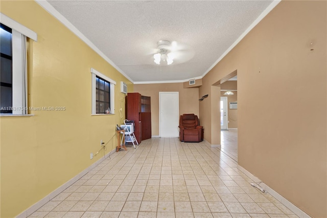 hallway with visible vents, crown molding, baseboards, light tile patterned flooring, and a textured ceiling