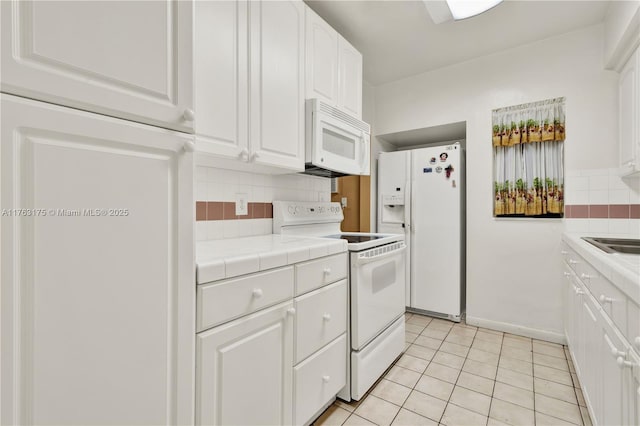 kitchen featuring tile counters, decorative backsplash, light tile patterned flooring, white appliances, and white cabinetry