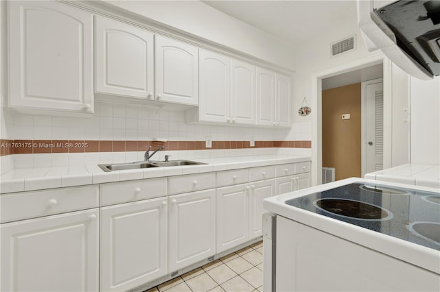 kitchen featuring visible vents, backsplash, white range with electric stovetop, white cabinetry, and a sink