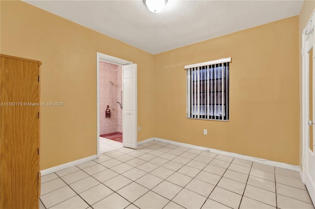 spare room featuring light tile patterned floors and baseboards