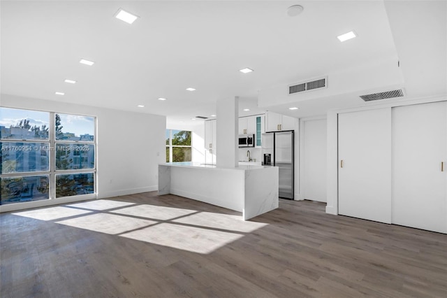 unfurnished living room with a sink, visible vents, and wood finished floors