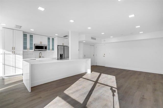 kitchen with visible vents, a sink, stainless steel appliances, white cabinets, and a center island