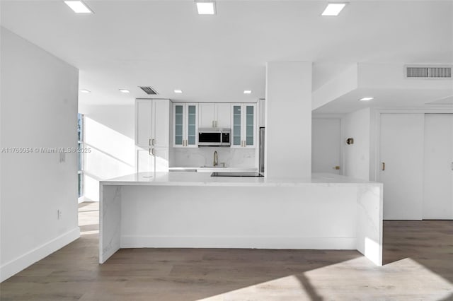 kitchen featuring glass insert cabinets, white cabinets, wood finished floors, and visible vents