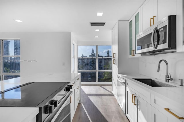 kitchen featuring visible vents, a sink, tasteful backsplash, white cabinetry, and stainless steel appliances