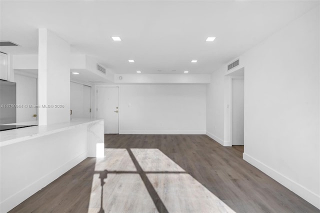 empty room with wood finished floors, visible vents, and baseboards