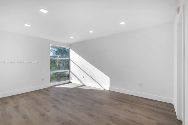 spare room with baseboards and wood finished floors