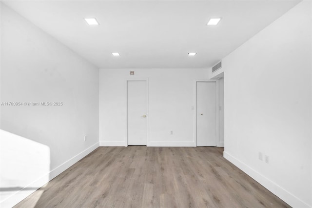 unfurnished room featuring light wood-style floors, baseboards, and visible vents