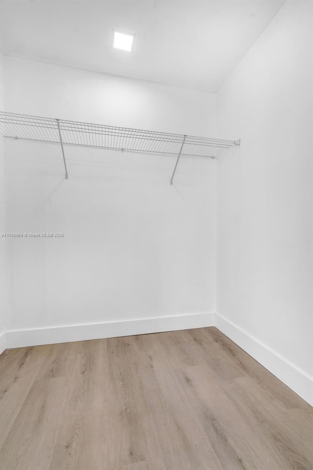 walk in closet with wood finished floors