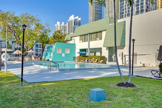 view of pool featuring a view of city and a lawn