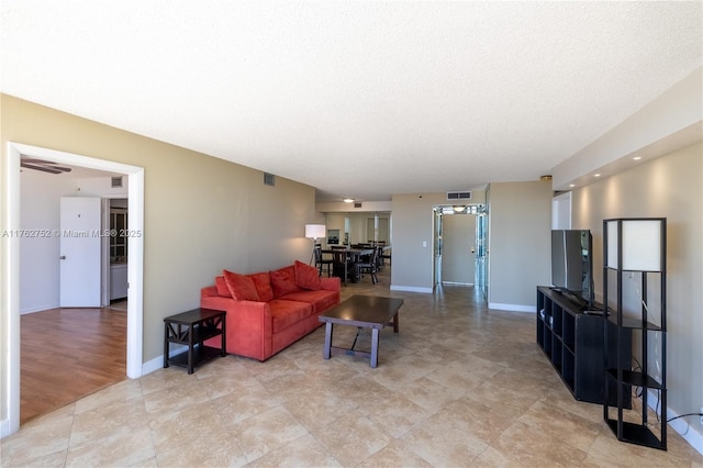 living area featuring visible vents, a textured ceiling, and baseboards