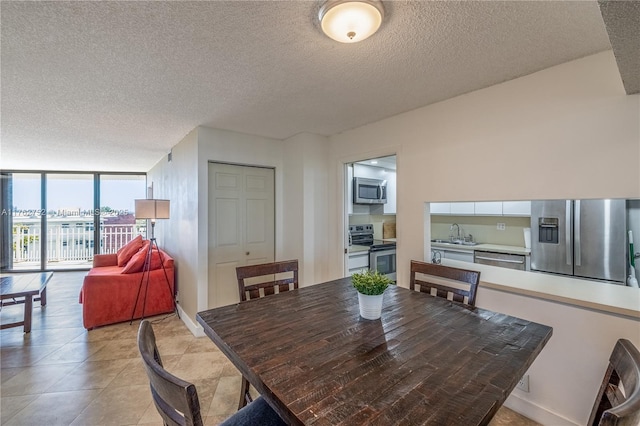 dining space with light tile patterned floors, a textured ceiling, baseboards, and expansive windows