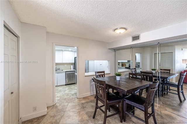 dining space featuring visible vents, baseboards, and a textured ceiling