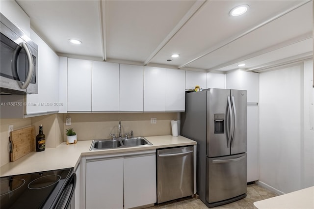 kitchen with recessed lighting, a sink, light countertops, appliances with stainless steel finishes, and white cabinetry