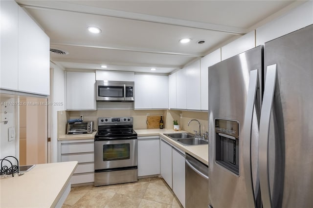 kitchen with visible vents, a sink, white cabinetry, appliances with stainless steel finishes, and light countertops