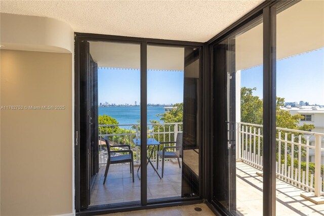 4000 Towerside Ter Unit 610, Miami, FL 33138 - entryway featuring a wall of windows, a water view, tile patterned flooring, and a healthy amount of sunlight